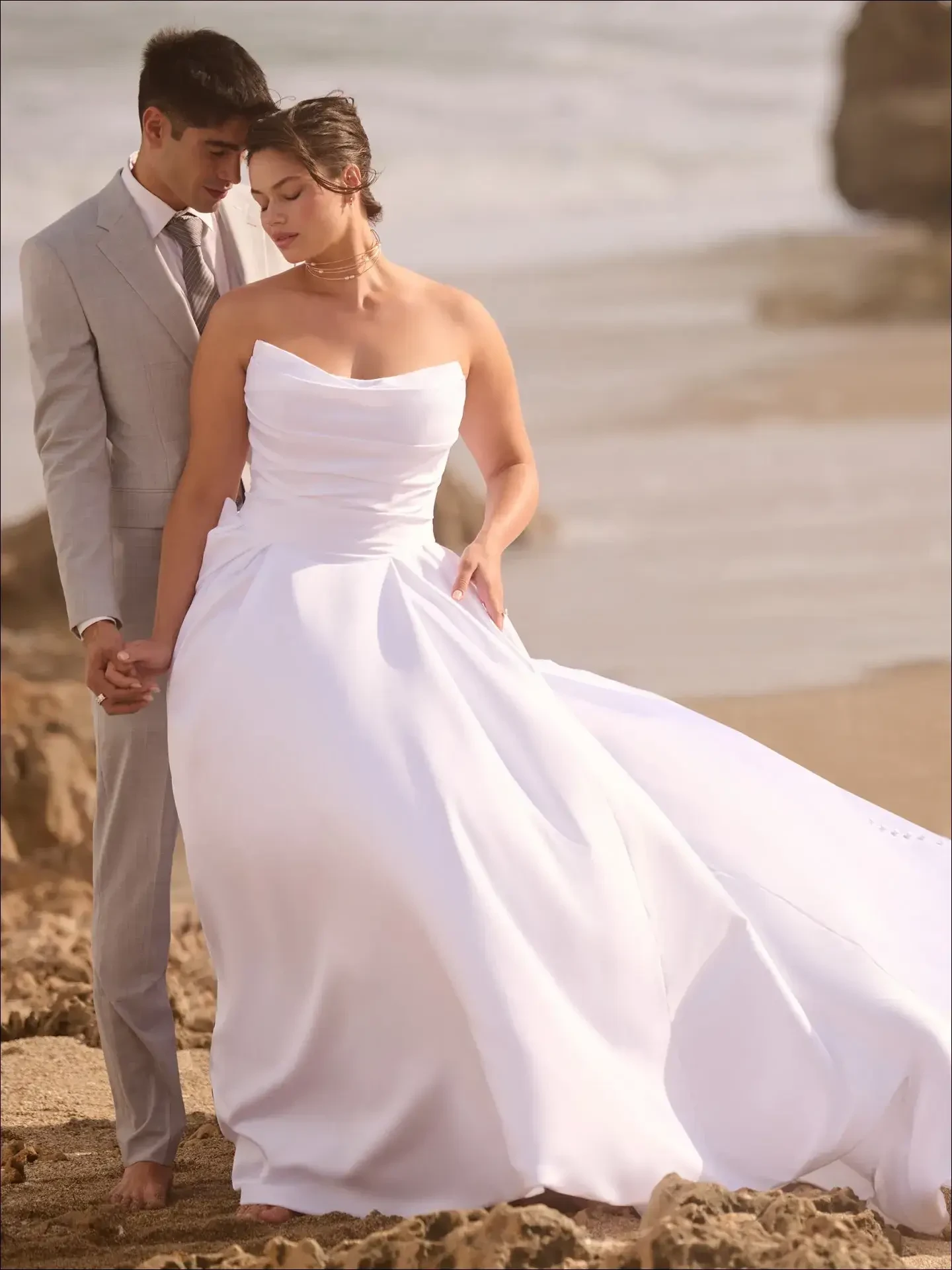 model is wearing a strapless plus size ball gown wedding dress