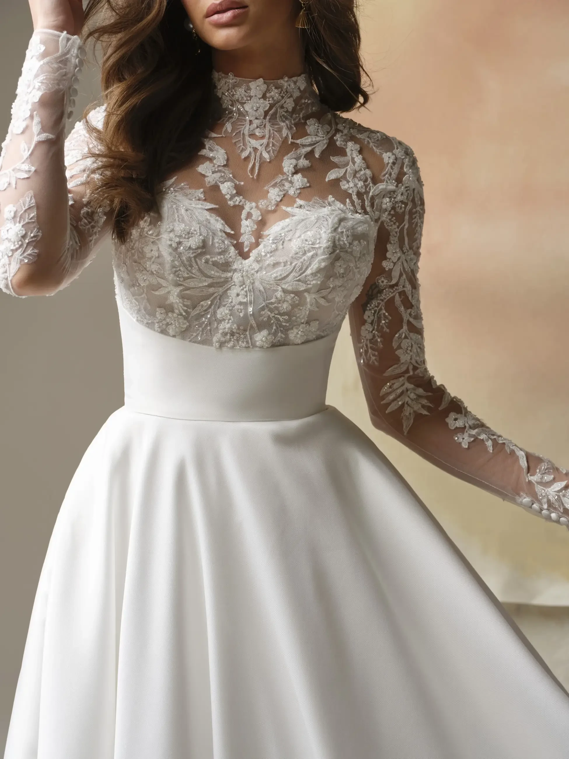 Bride wearing an elegant white dress with intricate lace detailing on the bodice and sleeves, exuding a classic and romantic tone.
