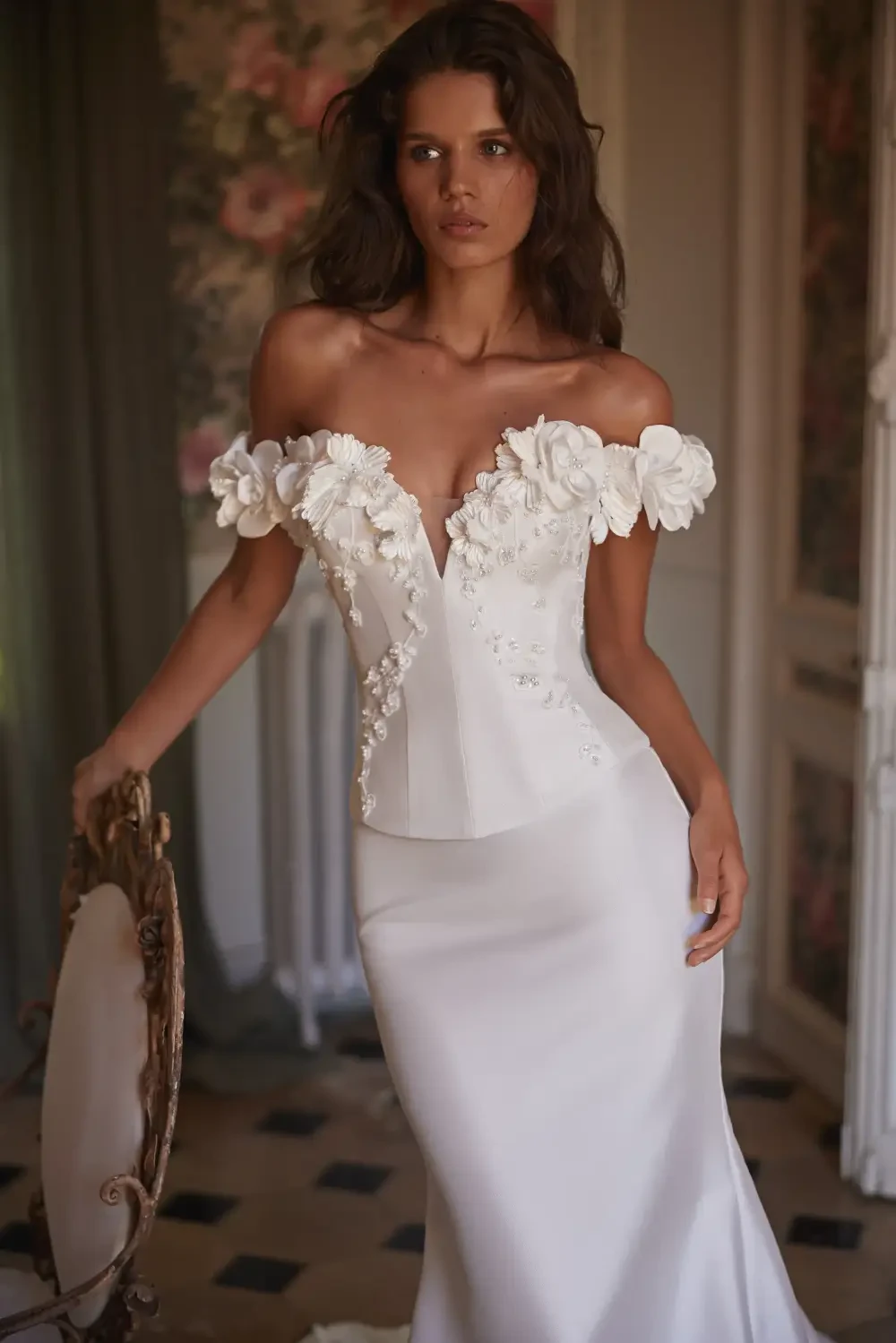 model is wearing an off the shoulder 3d floral applique bridal gown
